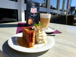 a plate with a piece of cake and a drink at Komforthotel Butjadinger Tor in Nordenham