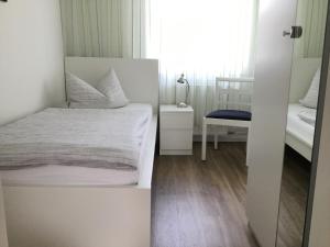 een witte slaapkamer met een bed en een stoel bij Ferienhaus Am Yachthafen in Rendsburg