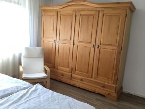 een slaapkamer met een grote houten kast en een stoel bij Ferienhaus Am Yachthafen in Rendsburg