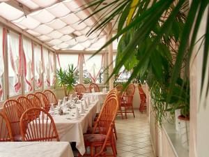 uma sala de jantar com mesas, cadeiras e plantas em Hotel Etschquelle em Resia