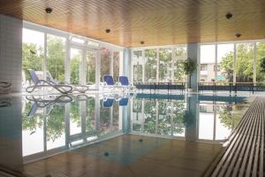 a pool with chairs and a table in a building at Hotel Am Friesenstrand in Butjadingen