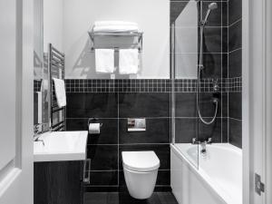 a black and white bathroom with a toilet and a sink at Qudos in Salisbury