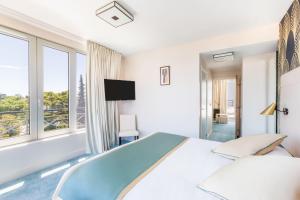 een witte slaapkamer met een groot bed en ramen bij Best Western Hôtel Journel Antibes Juan-les-Pins in Antibes