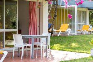 einen Tisch und Stühle auf einer Veranda mit rosa Blumen in der Unterkunft Apartamentos Turisticos Pinhal Da Marina in Vilamoura