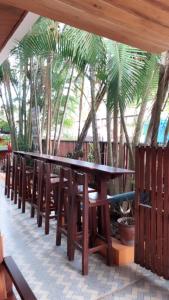 une rangée de tables et de chaises en bois devant les palmiers dans l'établissement Luang Prabang Hostel, à Luang Prabang