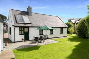 una casa bianca con tavolo e ombrellone verde di Fado Cottage Kenmare a Kenmare