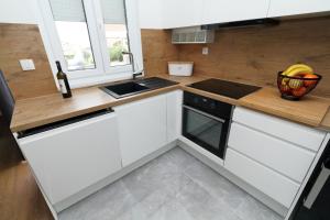 cocina con armarios blancos y encimera de madera en Apartments Pivac, en Makarska