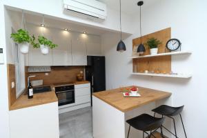 una cocina con armarios blancos y una barra con taburetes en Apartments Pivac, en Makarska