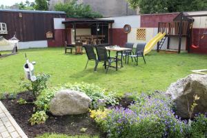 a yard with chairs and a table and some flowers at Windrose in Liepāja