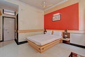 - une chambre dotée d'un lit avec un mur rouge dans l'établissement Bharati Lodge, à Hubli