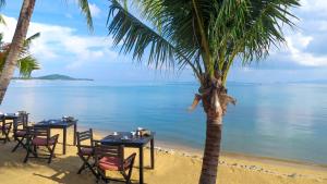 een restaurant op het strand met tafels en stoelen bij Paradise Beach Resort, Koh Samui - SHA Extra Plus in Mae Nam