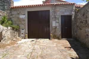 2 portes brunes sur un bâtiment en pierre avec un trottoir dans l'établissement Quinta do Real - Casa de Campo, à Viana do Castelo