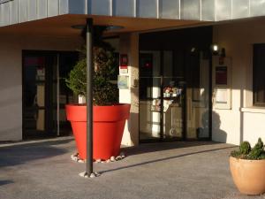 una gran olla naranja con una planta delante de un edificio en ibis Lyon Est Beynost, en Beynost