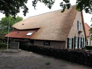 ein Gebäude mit einem Dach mit einem Schild darauf in der Unterkunft B & B De Pimpelmees in 's-Gravenmoer