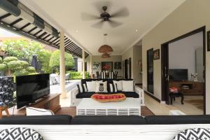 een woonkamer met een bank en een flatscreen-tv bij Villa Bloom 1 - 4 bedrooms, 4 bathrooms, private pool close to the beach in Seminyak