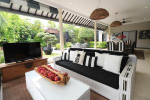 een woonkamer met een bank en een tv bij Villa Bloom 1 - 4 bedrooms, 4 bathrooms, private pool close to the beach in Seminyak