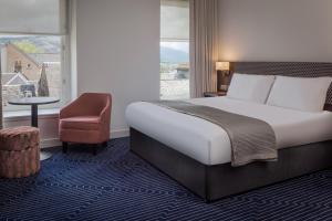 una camera con un letto e una sedia e una finestra di Hotel Colessio a Stirling