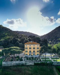 ein großes gelbes Gebäude mit einem Berg im Hintergrund in der Unterkunft Hotel Villa Casanova in Lucca