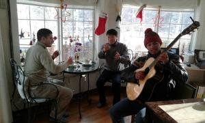 Un gruppo di uomini seduti in una stanza che suonano la chitarra di Fermata Pension a Pyeongchang