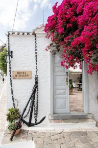 um edifício branco com flores cor-de-rosa e uma porta em Hotel Miranda em Hydra