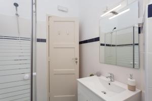 a white bathroom with a sink and a mirror at MouraLua in Sintra