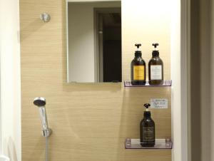 un bagno con 3 bottiglie su scaffali in uno specchio di Hotel Wing International Korakuen a Tokyo