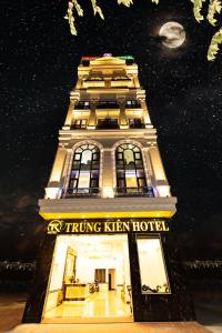 ハイフォンにあるTRUNG KIÊN HOTELの夜間の看板が貼られた高層ビル