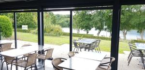 a patio with tables and chairs and a view of the water at Gite de la Haie in Apremont