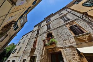 um antigo edifício de pedra com plantas numa janela em Pyrotima Apartments em Zadar