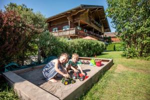 two children playing in a sandbox with toy trucks at Appartement Unterbering in Söll