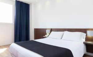 - une chambre avec un grand lit blanc et des rideaux bleus dans l'établissement Hotel Olympia Universidades, à Valence