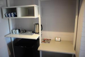 a kitchen with a counter with a coffee maker on a shelf at Atrium Hotel Mandurah in Mandurah