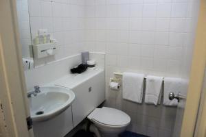 a white bathroom with a toilet and a sink at Atrium Hotel Mandurah in Mandurah