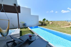 einen Pool mit Stühlen und einer Hängematte neben einem Haus in der Unterkunft Feliz Villa Suite Irabujima Sawada in Miyako-jima