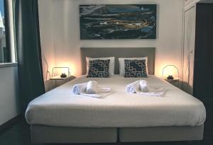 ein Schlafzimmer mit einem großen Bett mit zwei Handtüchern darauf in der Unterkunft Pine House - Faro Airport, Beach and City Center in Faro