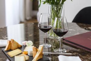 dos copas de vino tinto y queso en una mesa en Hôtel Cardinal Bordeaux Centre, en Burdeos