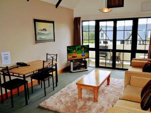 een woonkamer met een tafel, een bank en een tv bij Salty Dog Inn in Snells Beach