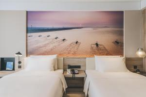 twee bedden in een kamer met een foto van een strand bij Atour Hotel Haining Leather City South Gate in Haining