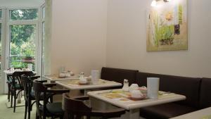 a dining room with tables and chairs and a painting at Entrée Groß Borstel Garni Hotel in Hamburg