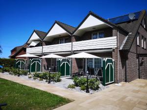 un edificio con puertas y sombrillas verdes y blancas en Haus Daniel, en Neuharlingersiel