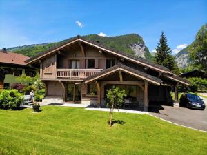 ein großes Holzhaus mit grünem Rasen davor in der Unterkunft Chalet Luxe Les Mélèzes in Samoëns