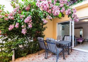 un tavolo e sedie sotto un albero con fiori rosa di Apartments Dijana a Zara (Zadar)