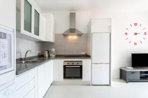 una cocina con armarios blancos y un reloj en la pared en Apartamento Orlando - Costa Adeje, en Adeje