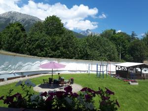 un patio con una sombrilla rosa y un parque infantil en A1 Štart, en Starý Smokovec