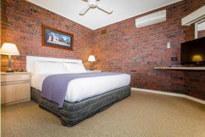 ein Schlafzimmer mit einem Bett und einer Ziegelwand in der Unterkunft Hotel Bruce County in Mount Waverley