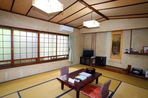 een woonkamer met een tafel, stoelen en ramen bij Hinode Ryokan in Ise