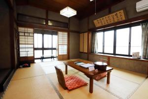 een kamer met een tafel, stoelen en ramen bij Hinode Ryokan in Ise