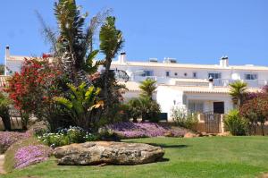 een groot wit gebouw met bloemen en een rots bij Ocean Villas Luz in Luz