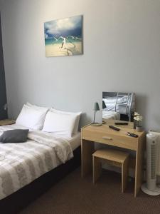 - une chambre avec un lit et un bureau avec une photo sur le mur dans l'établissement Tregonholme Guesthouse, à Bournemouth