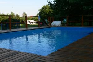 een blauw zwembad met een houten terras bij Dworek Karpińskich in Sandomierz